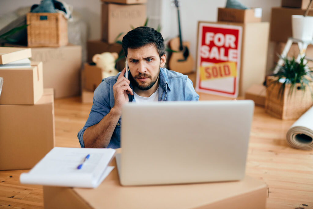 distraught man making a phone call after moving into a new home.